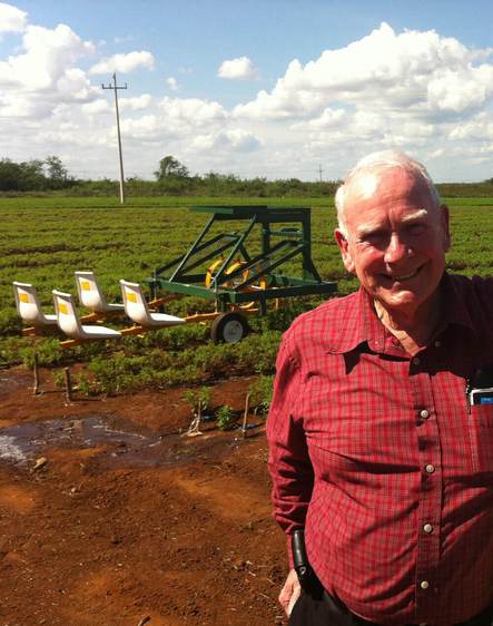 man smiling in front of tractor in a field