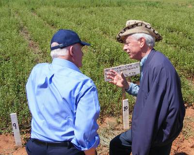 two men talking in front of a field