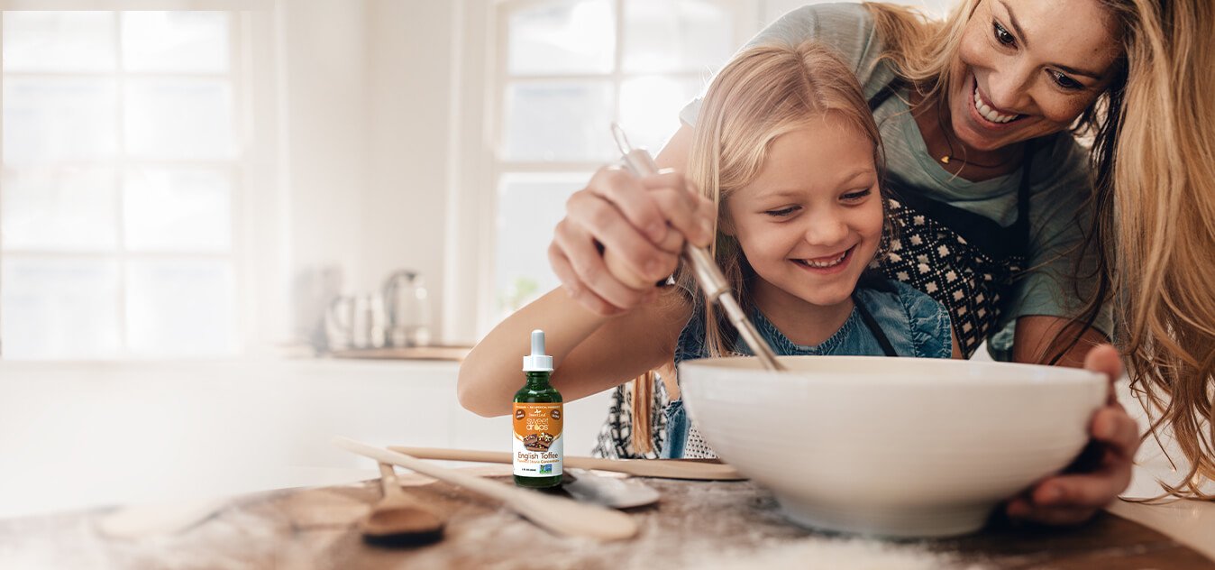 mother and daughter using a whisk in a mixing bowl with stevia drops beside them on countertop