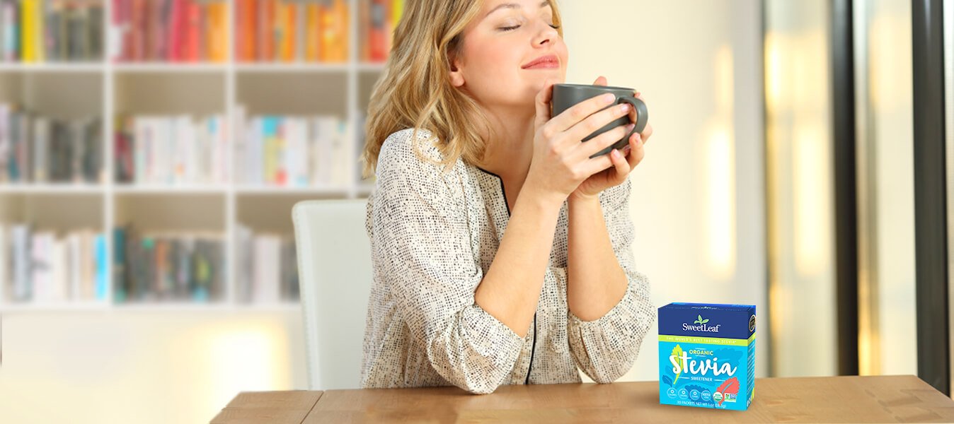 woman holding a mug and enjoying a cup of coffee with a box of stevia on the counter